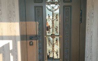 входная дверь в коттедж с тройным тонированным стеклопакетом и кованой решеткой - общий вид
